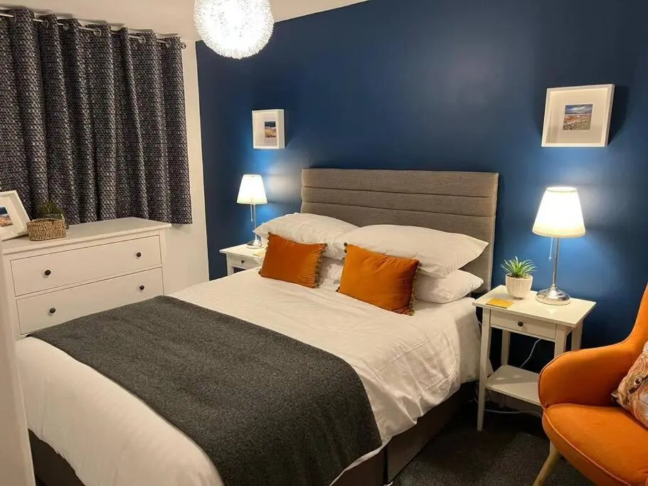 a bedroom with a bed and a blue wall at Delightful, central 3 bedroom house with garden & free parking in Inverness