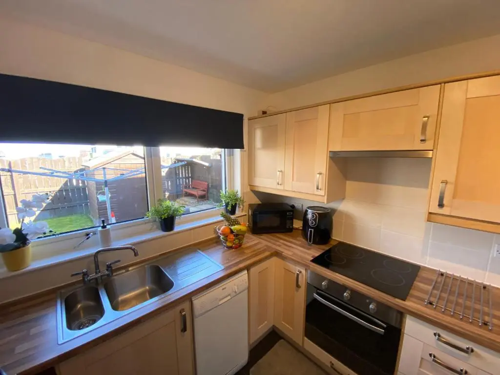 a kitchen with wooden cabinets and a sink and a window at Delightful, central 3 bedroom house with garden & free parking in Inverness