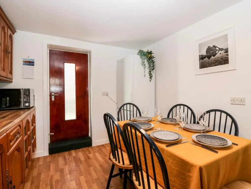 a dining room with a table with chairs and a kitchen at 4 Gordon Street in Buckie