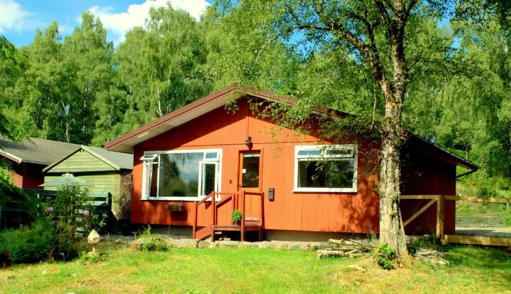 a small orange house with a tree in the yard at Torcroft Lodges in Drumnadrochit