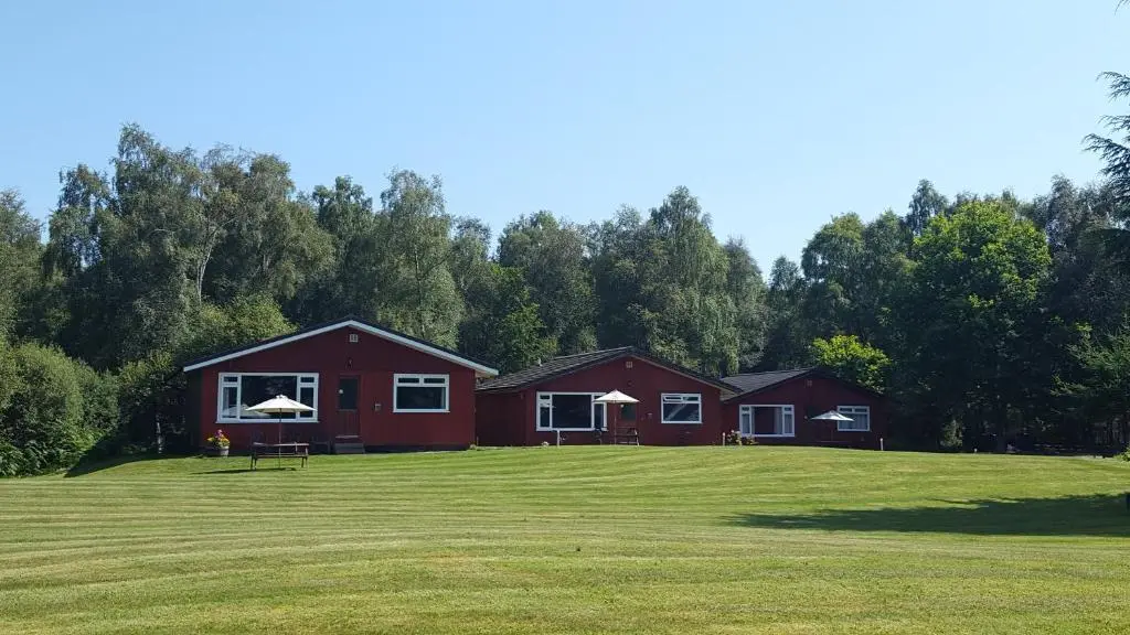 a red house on a large grassy field at Torcroft Lodges in Drumnadrochit