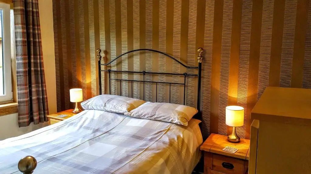 a bedroom with a bed with two lamps on tables at Torcroft Lodges in Drumnadrochit