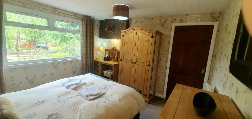 a small bedroom with a bed and a window at Torcroft Lodges in Drumnadrochit