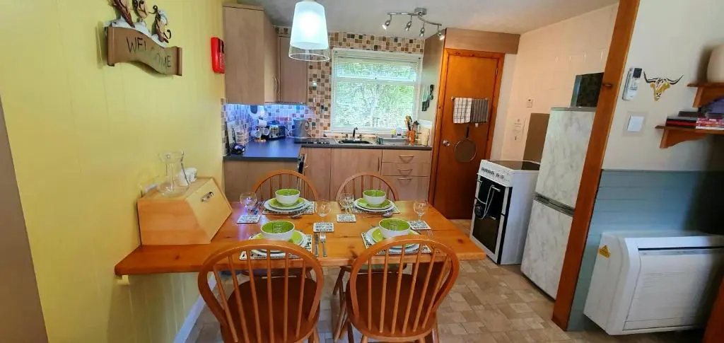 a kitchen with a wooden table and four chairs at Torcroft Lodges in Drumnadrochit