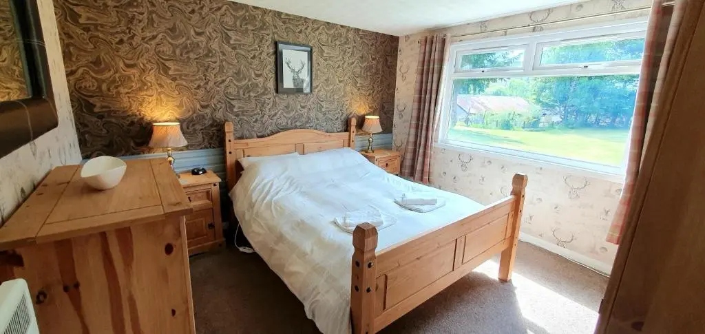a bedroom with a bed and a desk and a window at Torcroft Lodges in Drumnadrochit