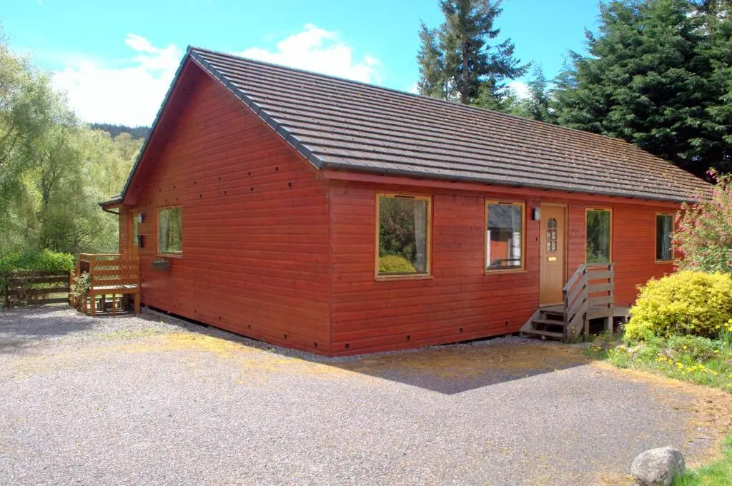 a small red cabin with a porch and a staircase at Torcroft Lodges in Drumnadrochit