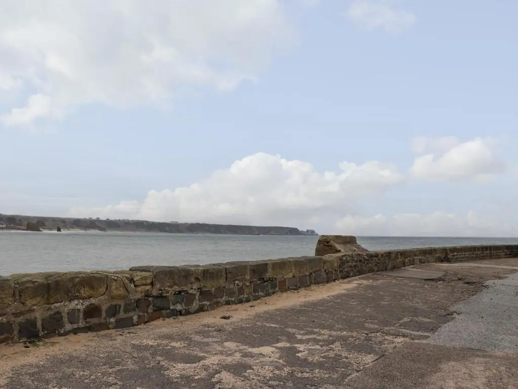 a stone wall next to a body of water at Eider Cottage in Buckie