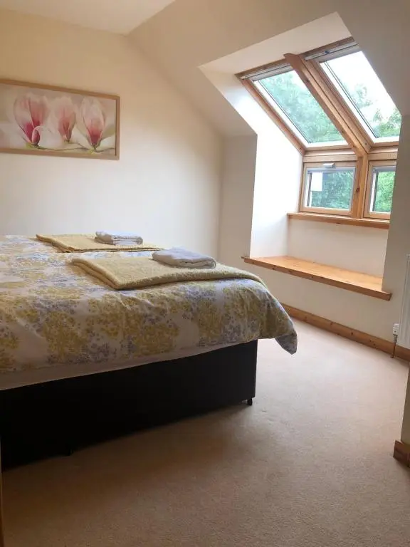 a bedroom with a bed and two windows at Tulach Ard in Grantown on Spey