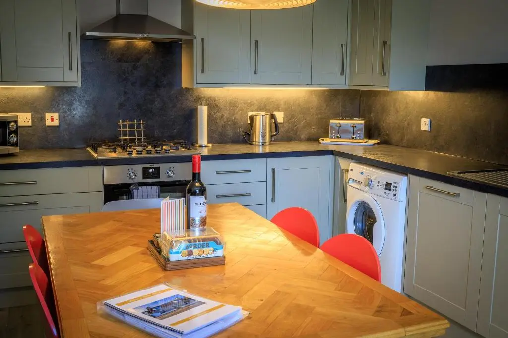 a kitchen with a wooden table with a bottle of wine at Cosy Cottage in Fishertown, Nairn - Free Parking & Pets welcome in Nairn