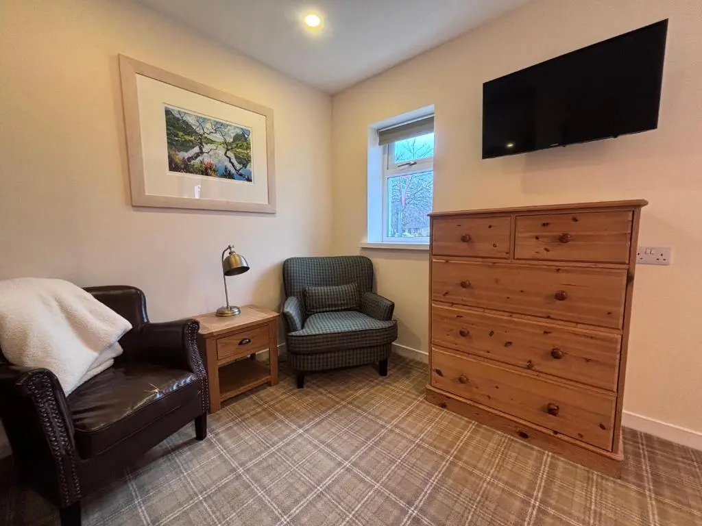 a bedroom with a dresser and a tv and a chair at The Ullapool Rooms in Ullapool