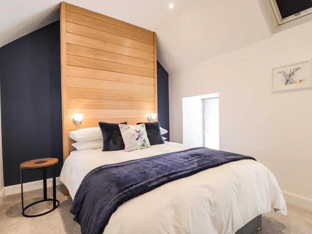 a bedroom with a large bed with a wooden headboard at The Steading in Rogart