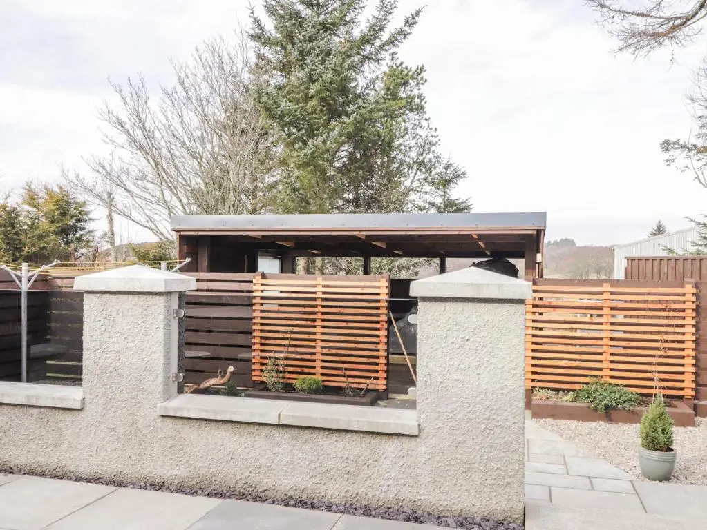a house with wooden shutters in a garden at The Steading in Rogart