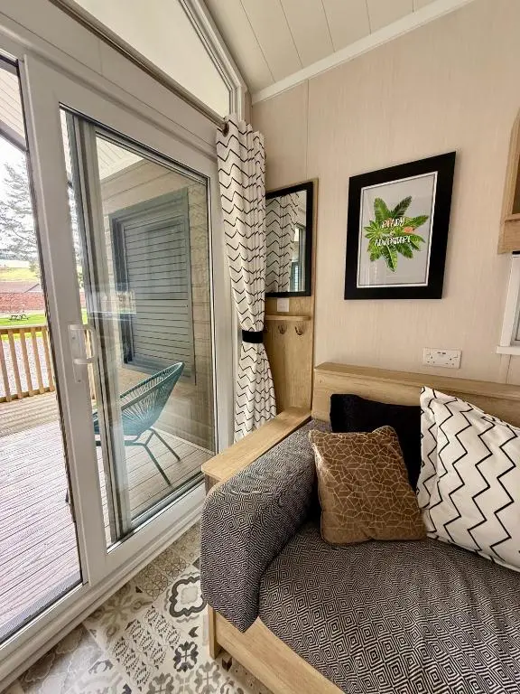 a living room with a couch and a sliding glass door at The Willy Gunn Pod - Beautiful, luxury pod in Aberlour