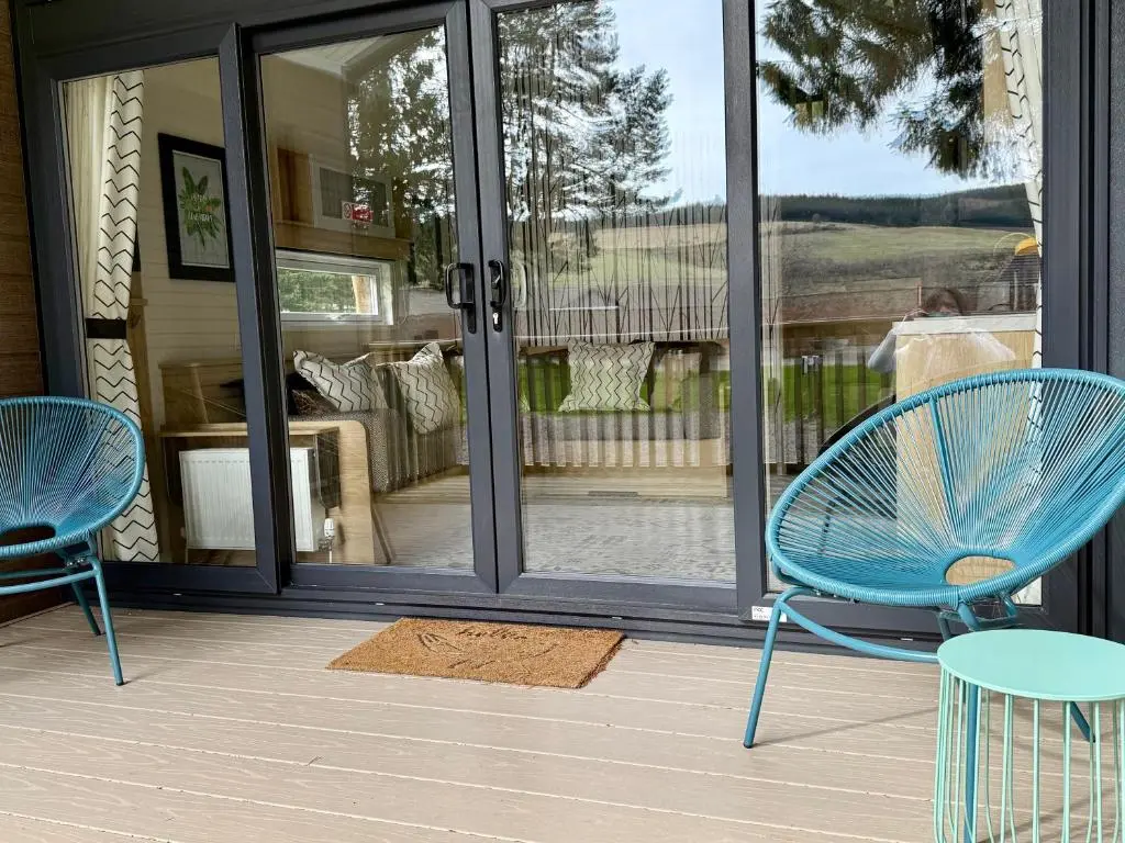 two blue chairs and a table on a porch at The Parr Pod - Beautiful, luxury pod in Aberlour