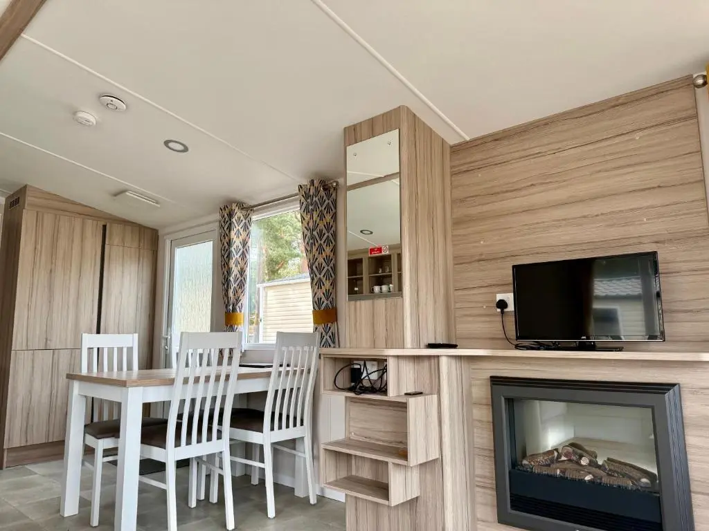 a dining room with a table and a tv and a fireplace at The Salmon Van - Beautiful, luxury static caravan in Aberlour