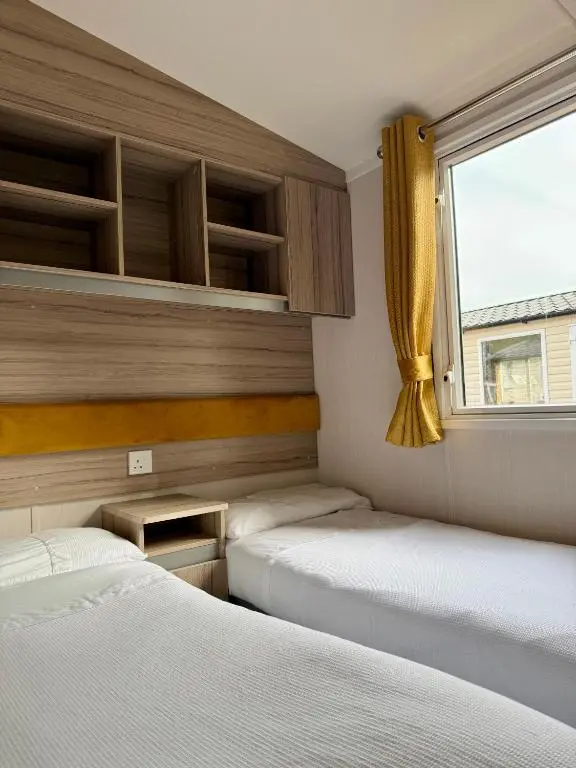 two beds in a small room with a window at The Salmon Van - Beautiful, luxury static caravan in Aberlour