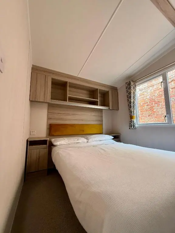 a small bedroom with two beds and a window at The Trout Van - Beautiful, luxury static caravan in Aberlour