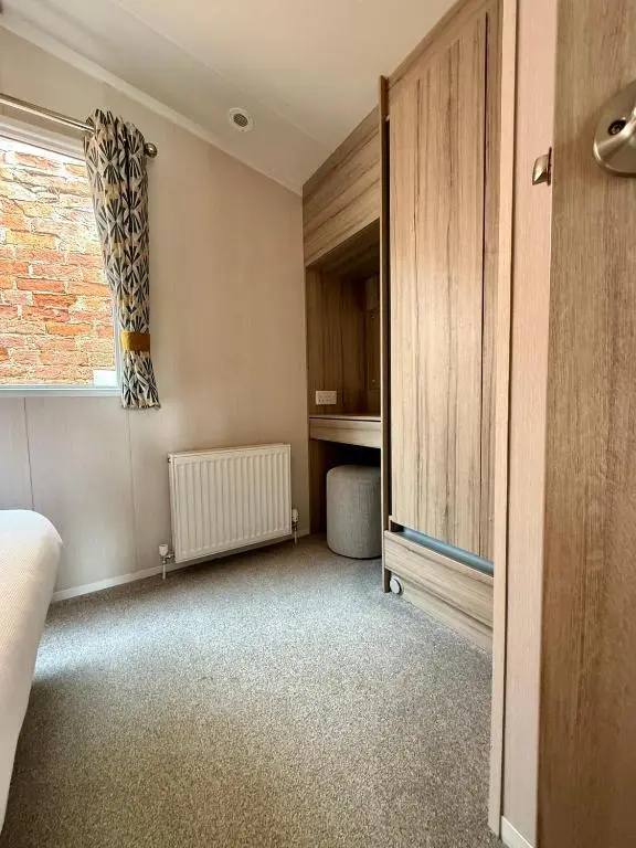 a bedroom with a bed and a window and a dresser at The Trout Van - Beautiful, luxury static caravan in Aberlour