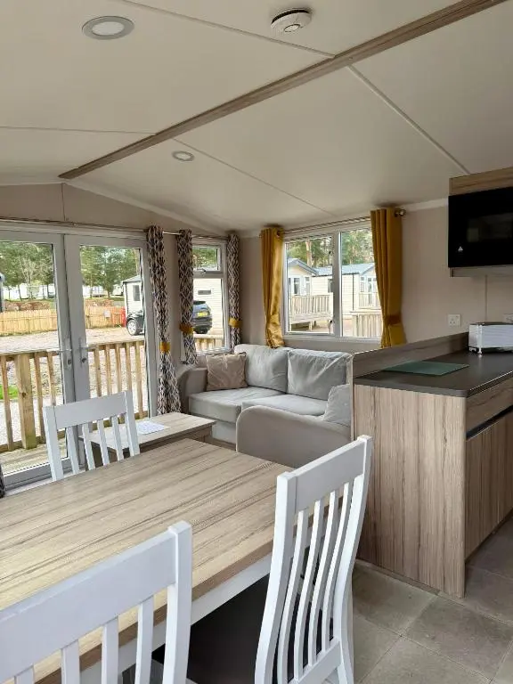 a caravan kitchen and living room with a table and chairs at The Trout Van - Beautiful, luxury static caravan in Aberlour