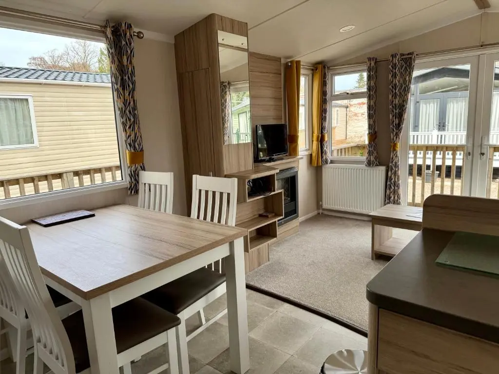 a dining room with a table and chairs and a television at The Fly Van - Beautiful, luxury static caravan in Aberlour