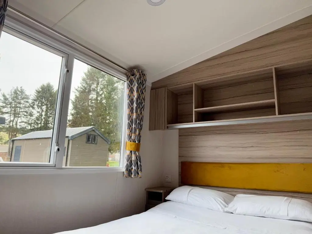 a bedroom with a bed and a large window at The Dram Van - Beautiful, luxury static caravan in Aberlour