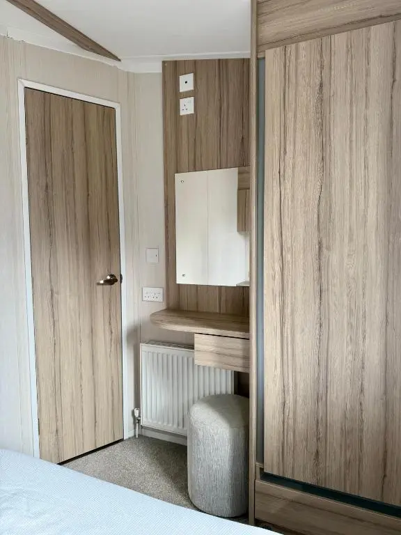 a bedroom with a bed and a door and a chair at The Dram Van - Beautiful, luxury static caravan in Aberlour