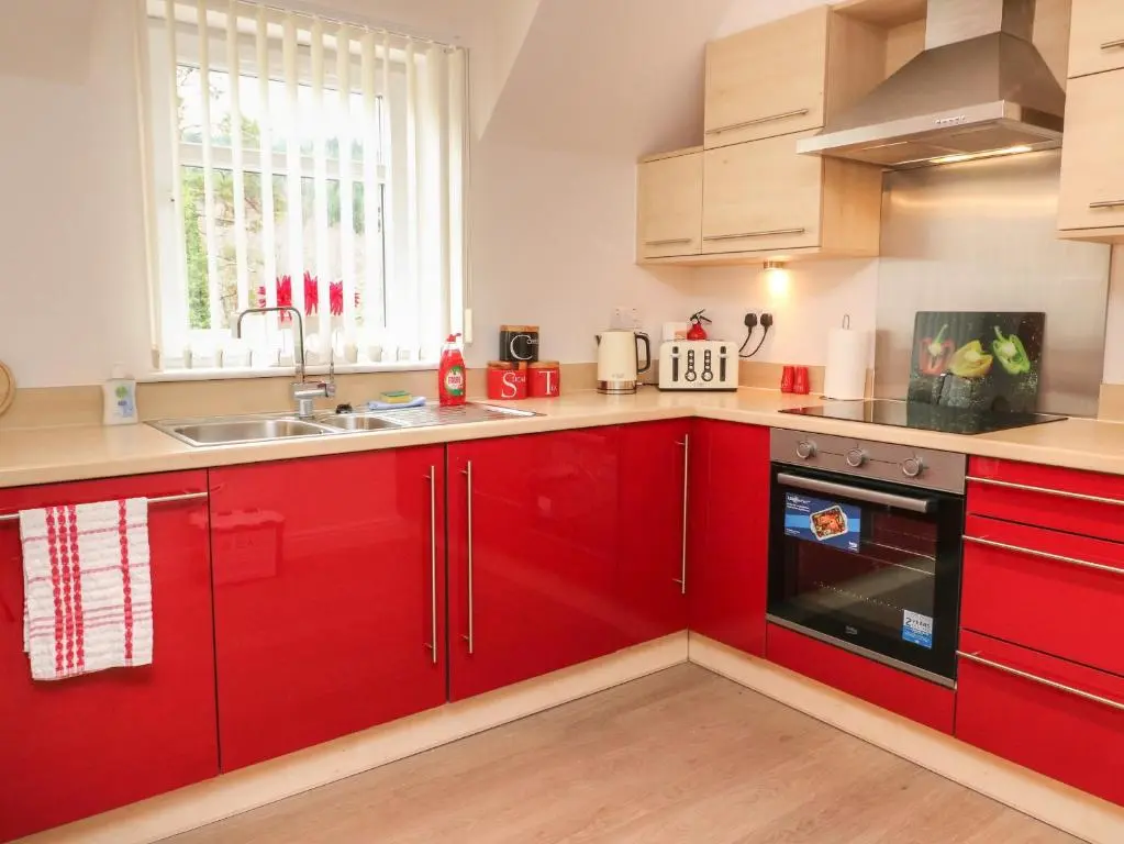a kitchen with red cabinets and a sink at 4 River Court in Invergarry