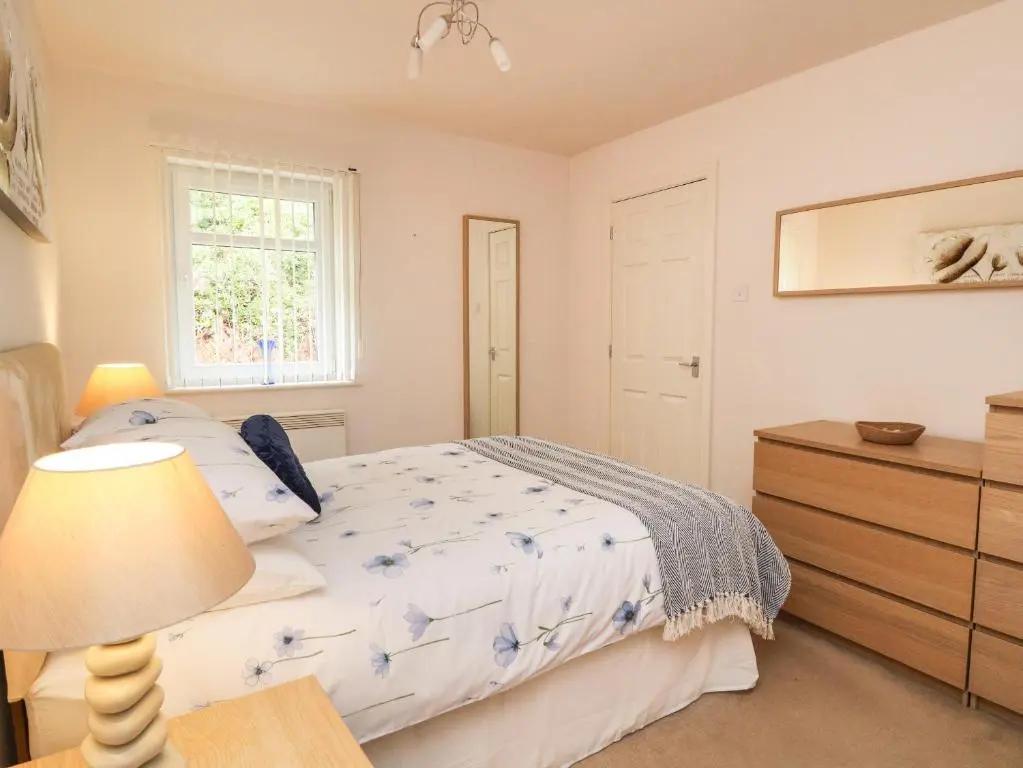 a bedroom with a bed and a dresser and a window at 4 River Court in Invergarry