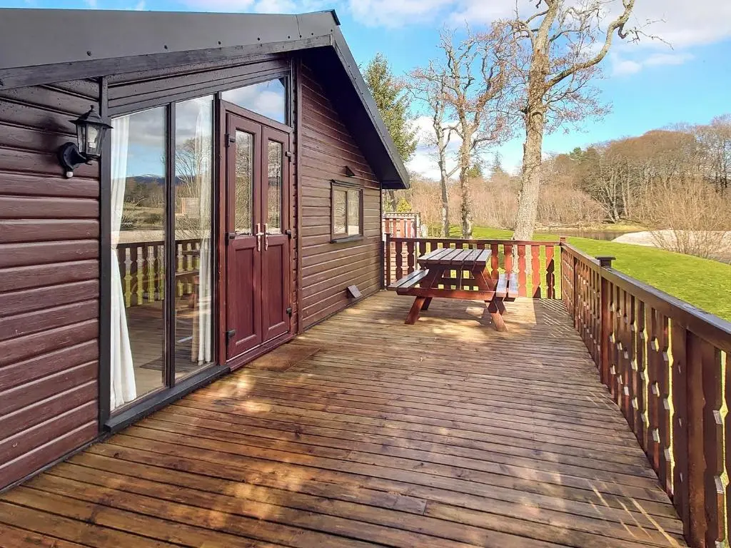 a wooden deck with a picnic table on it at 27 Aviemore Holiday Park in Aviemore