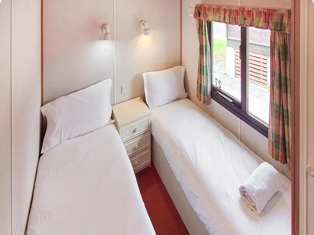 two beds in a small room with a window at 27 Aviemore Holiday Park in Aviemore