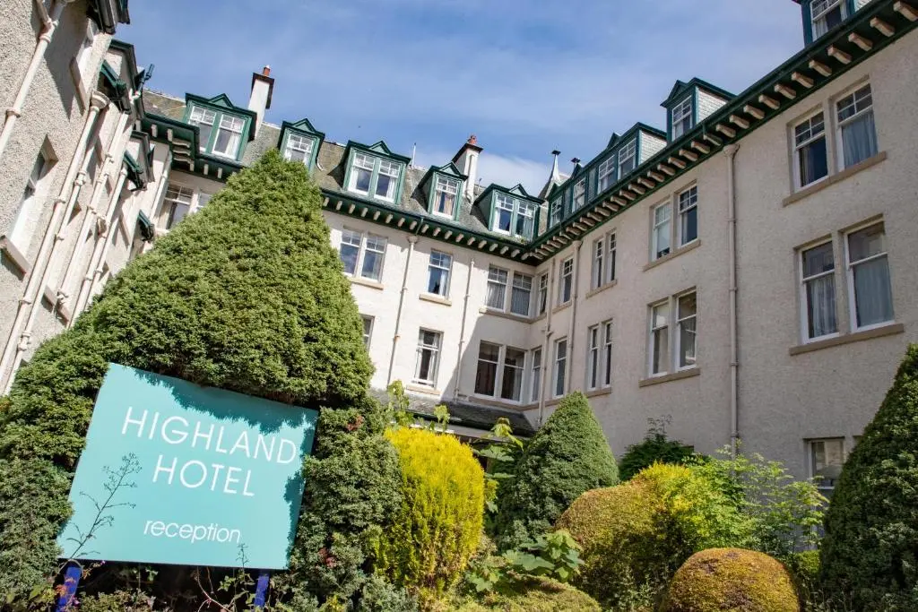 a hotel with a sign in front of a building at The Highland Hotel by Compass Hospitality in Strathpeffer