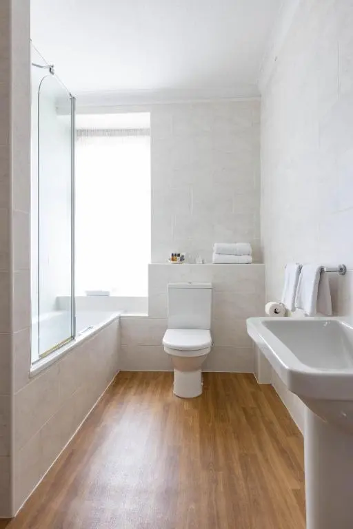 a white bathroom with a toilet and a sink at The Highland Hotel by Compass Hospitality in Strathpeffer