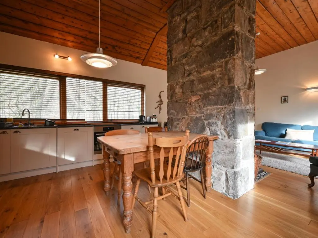 a kitchen with a wooden table and a stone wall at Holiday Home Riverside Cottage by Interhome in Inverness
