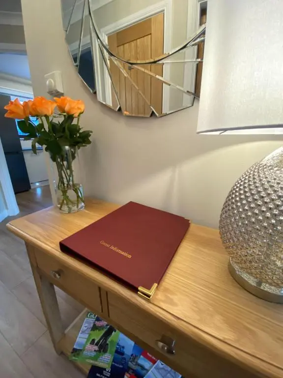 a book on a table with a vase of orange flowers at discoverNESS Apartment in Inverness