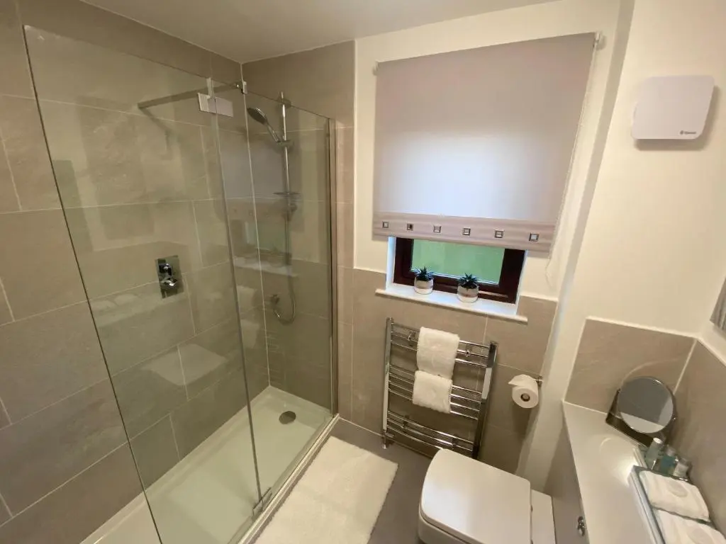 a bathroom with a shower and a toilet and a sink at discoverNESS Apartment in Inverness