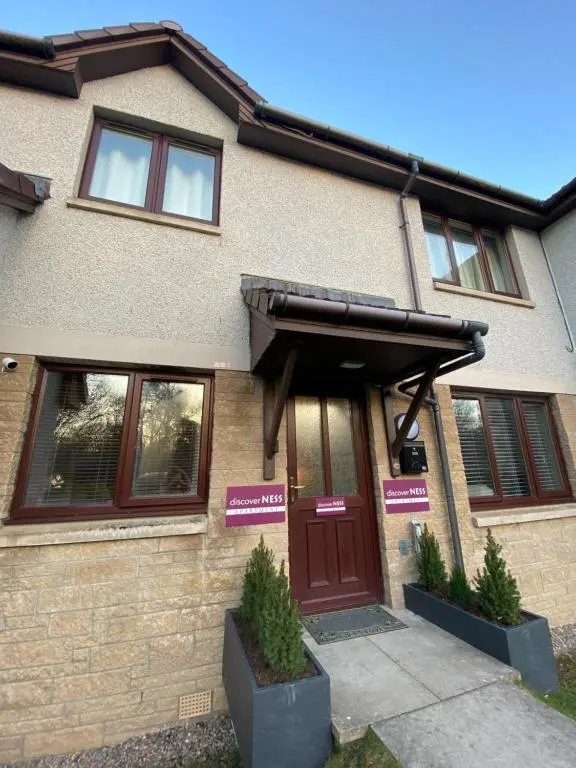 a house with a brown door with signs on it at discoverNESS Apartment in Inverness