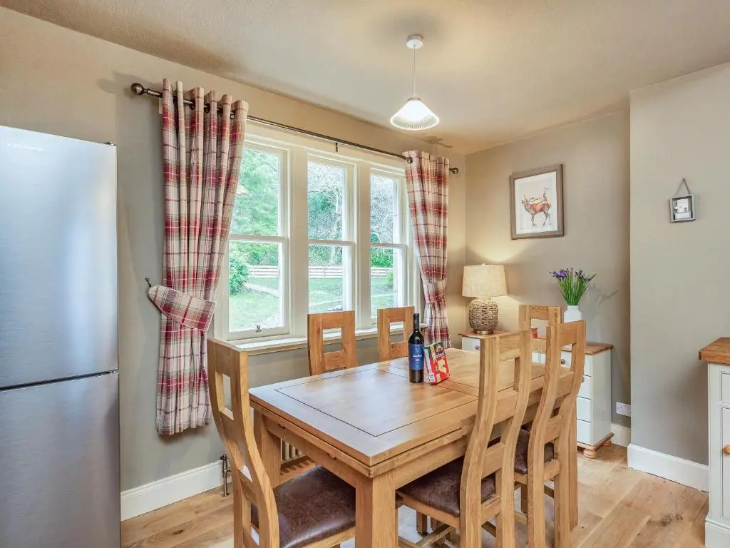 a dining room with a table and chairs and a refrigerator at East Lodge in Contin
