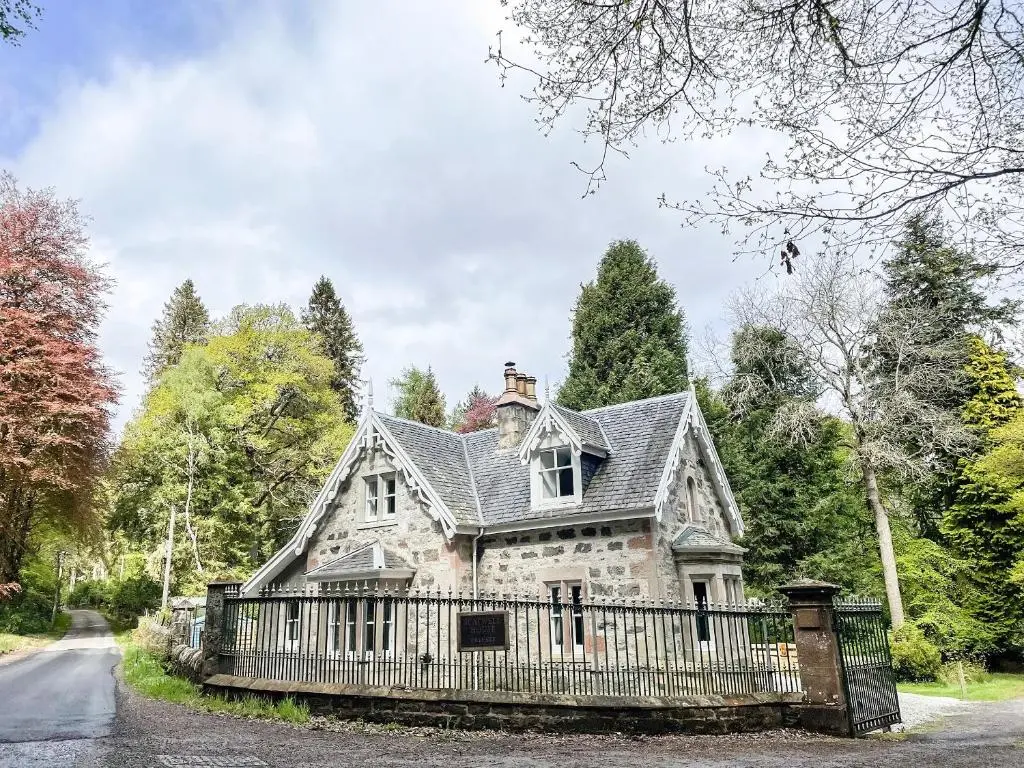 an old stone house with a fence at East Lodge in Contin