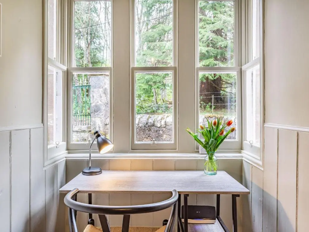 a table with a vase of flowers in a window at East Lodge in Contin