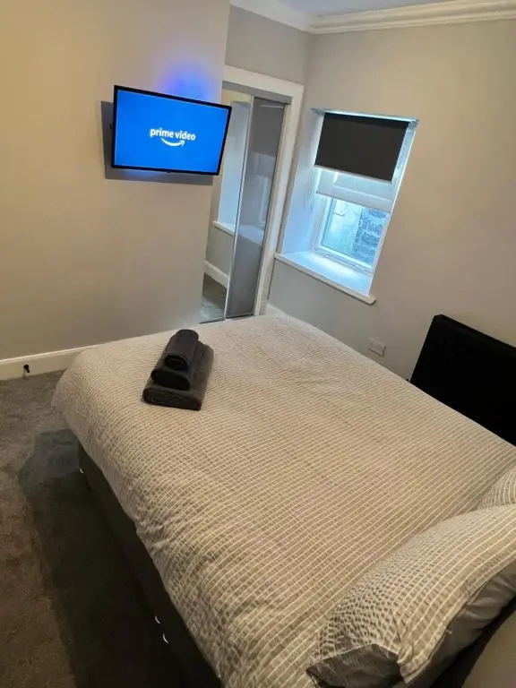 a bedroom with a bed with a flat screen tv on the wall at Town centre 2 bed luxury apartment in Wick
