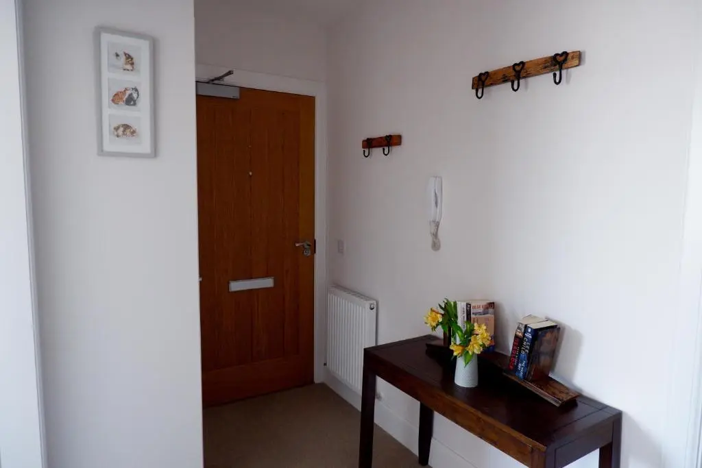 a hallway with a door and a table with flowers on it at No 7 Quiet, two bedroom Ground Floor Flat in Tornagrain Great for early Airport departures or late flights in Dalcross