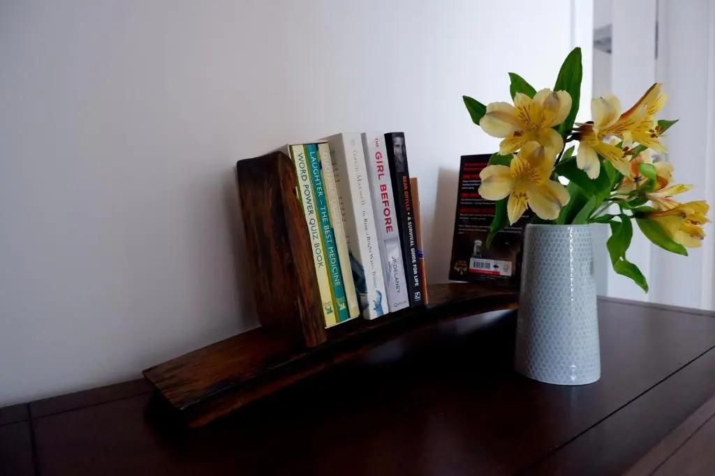 a vase with flowers on a table with books at No 7 Quiet, two bedroom Ground Floor Flat in Tornagrain Great for early Airport departures or late flights in Dalcross