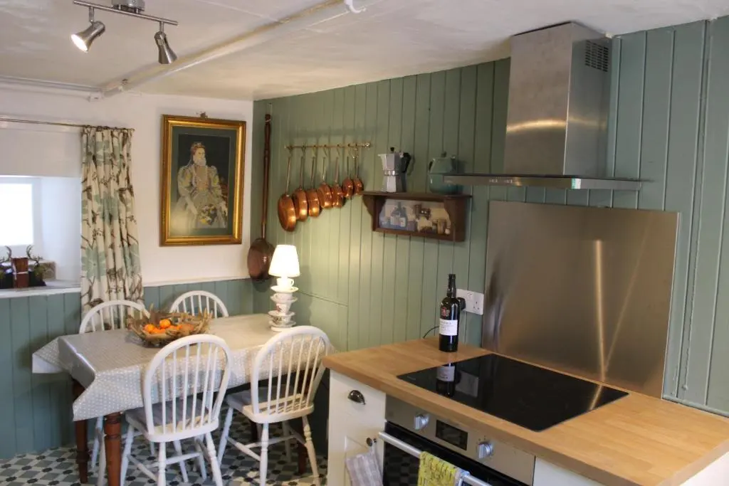 a kitchen with a sink and a counter with chairs at East Wing Lickleyhead Castle in Auchleven
