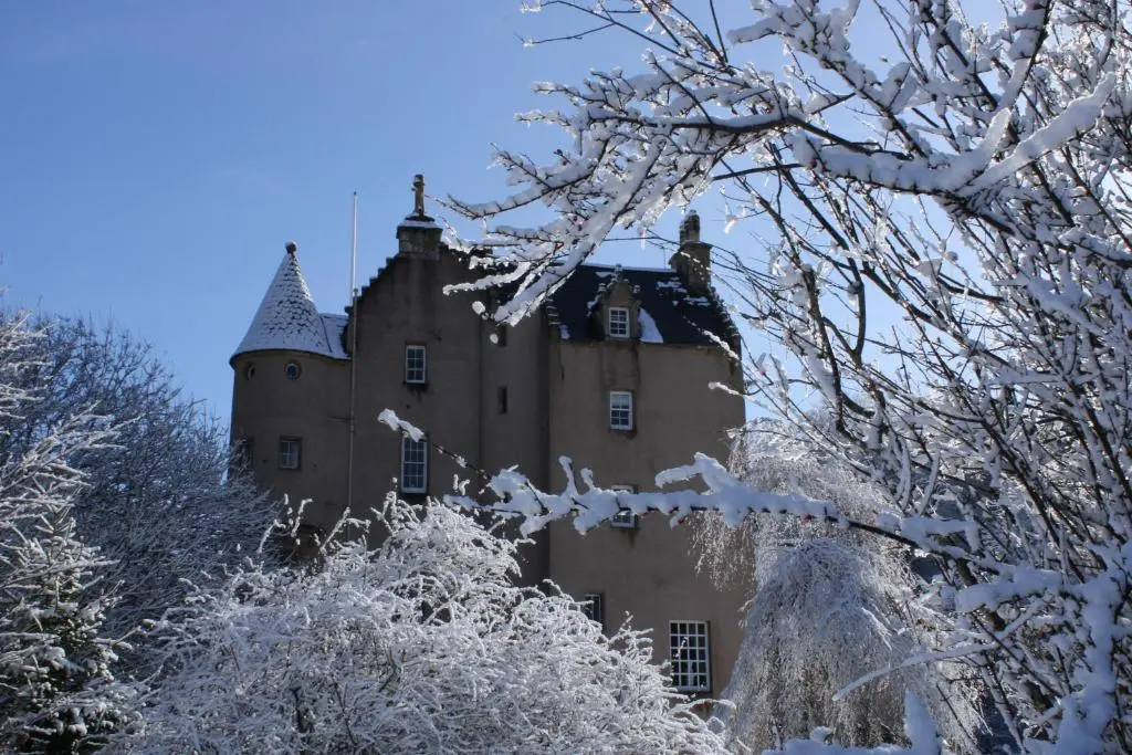 a castle covered in snow with trees in the foreground at East Wing Lickleyhead Castle in Auchleven