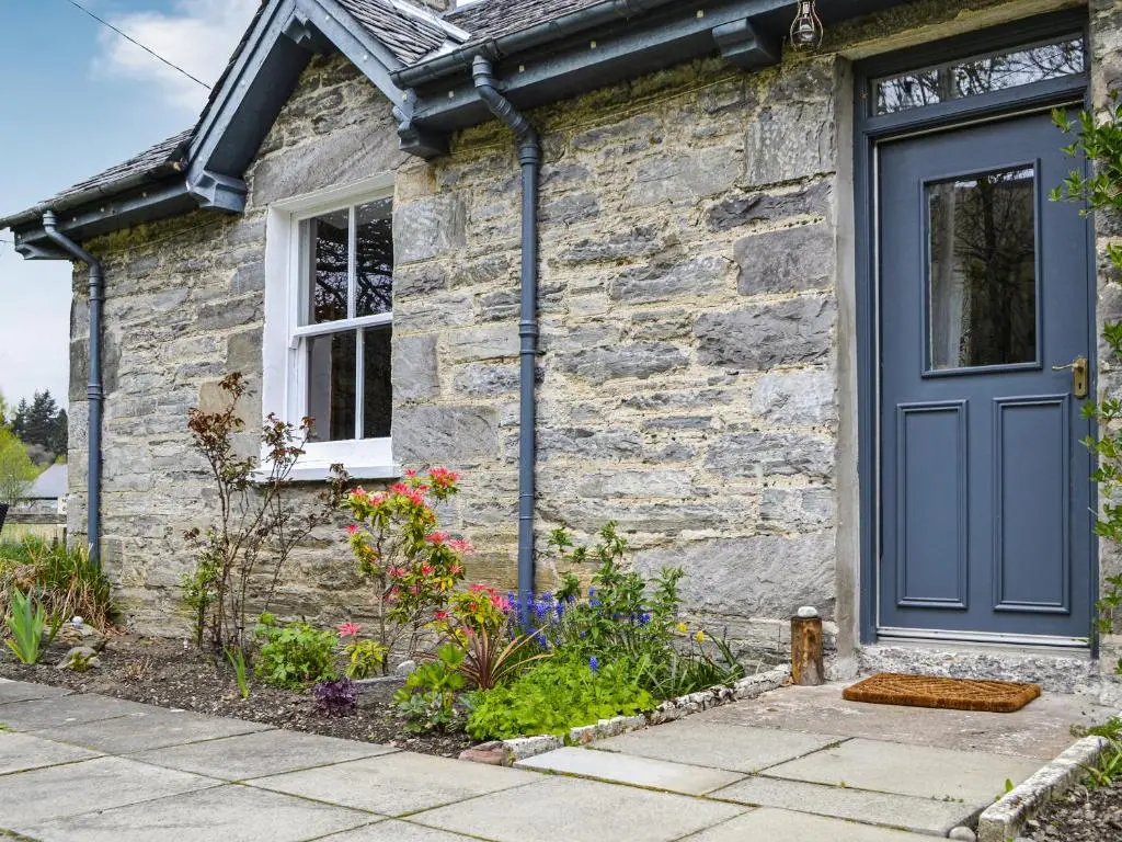 a stone house with a blue door at Riverside Cottage in Blair Atholl