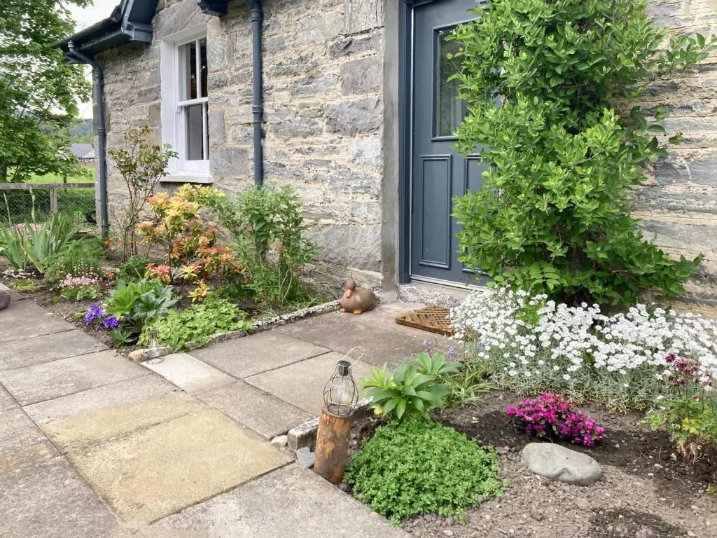 a front door of a house with flowers and a fire hydrant at Riverside Cottage in Blair Atholl