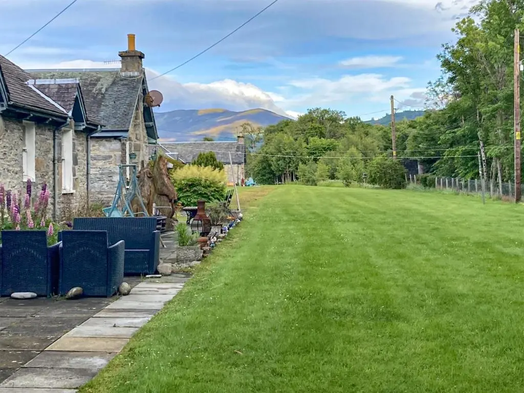 a house with a yard with green grass at Riverside Cottage in Blair Atholl