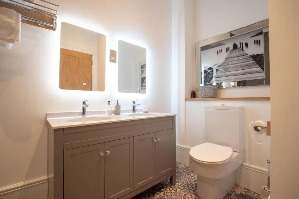 a bathroom with a toilet and a sink and mirror at Gordonston Apartments in Inverness