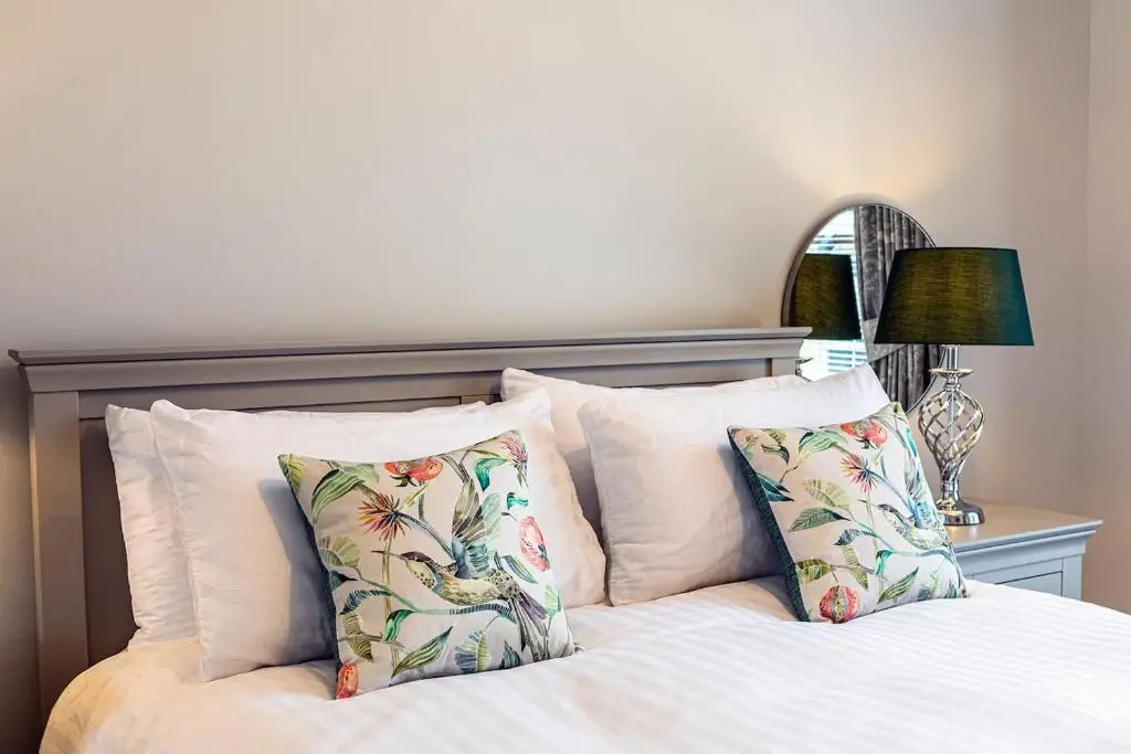 a bedroom with a bed with pillows and a lamp at Hedgefield House - Serene Top Floor Flat in Inverness
