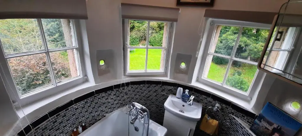 a bathroom with a sink and a tub and windows at West Wing Lickleyhead Castle in Auchleven